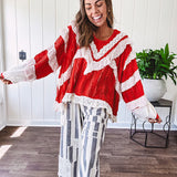 Apple red ruffle texture boho style long sleeved top with round neck and cream eyelet lace detail in a V shape across the front and on the sleeves and hem.
