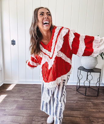 Apple red ruffle texture boho style long sleeved top with round neck and cream eyelet lace detail in a V shape across the front and on the sleeves and hem.