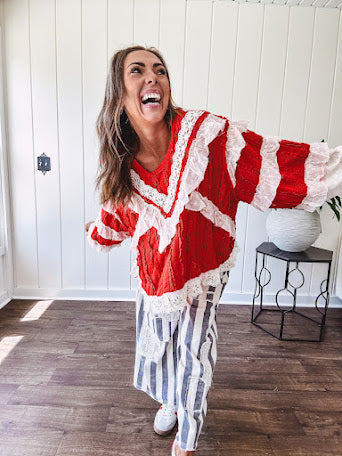 Apple red ruffle texture boho style long sleeved top with round neck and cream eyelet lace detail in a V shape across the front and on the sleeves and hem.