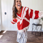 Apple red ruffle texture boho style long sleeved top with round neck and cream eyelet lace detail in a V shape across the front and on the sleeves and hem.