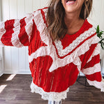 Apple red ruffle texture boho style long sleeved top with round neck and cream eyelet lace detail in a V shape across the front and on the sleeves and hem.