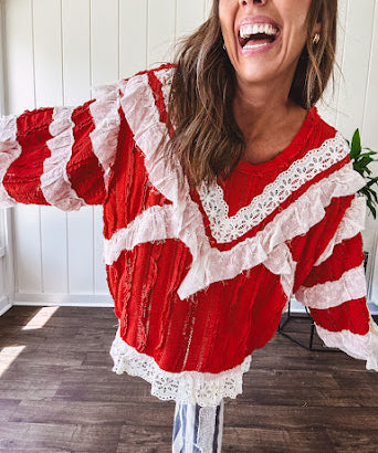 Apple red ruffle texture boho style long sleeved top with round neck and cream eyelet lace detail in a V shape across the front and on the sleeves and hem.