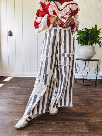 Wide leg cotton oversized gray and white striped pants with elastic back, button and zipper closure and crochet patch detail throughout.