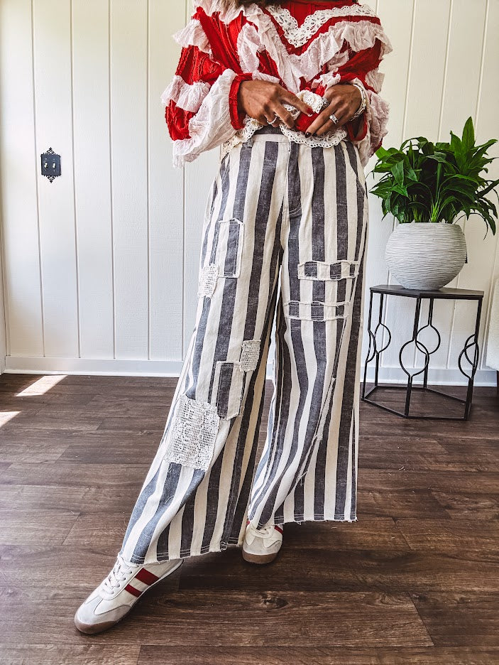 Wide leg cotton oversized gray and white striped pants with elastic back, button and zipper closure and crochet patch detail throughout.