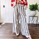 Wide leg cotton oversized gray and white striped pants with elastic back, button and zipper closure and crochet patch detail throughout.
