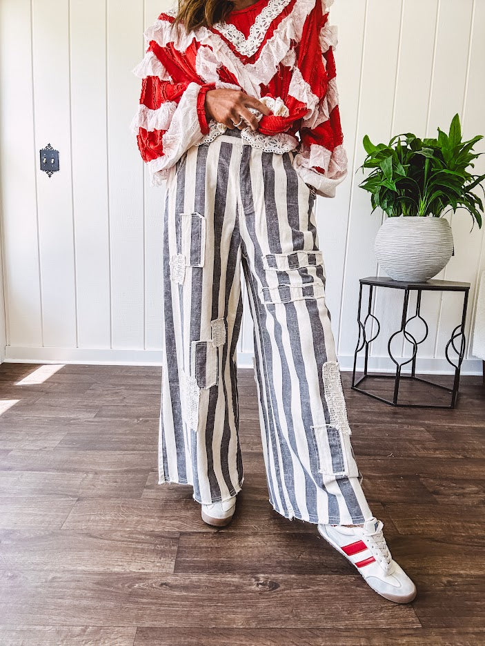 Wide leg cotton oversized gray and white striped pants with elastic back, button and zipper closure and crochet patch detail throughout.