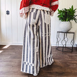 Wide leg cotton oversized gray and white striped pants with elastic back, button and zipper closure and crochet patch detail throughout.