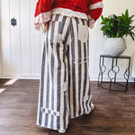 Wide leg cotton oversized gray and white striped pants with elastic back, button and zipper closure and crochet patch detail throughout.