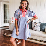 Slate blue dress with puffed, cuffed short sleeves, pockets, a contrasting coral collar and V neck, cuffs and trim and coral and pink embroidery at the yoke.