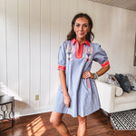 Slate blue dress with puffed, cuffed short sleeves, pockets, a contrasting coral collar and V neck, cuffs and trim and coral and pink embroidery at the yoke.