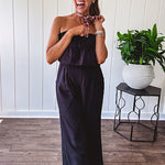 Fully lined black jumpsuit with sleeveless, ruffled bodice, smocked back, wide leg design and pockets at the pleated front.