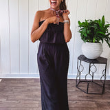 Fully lined black jumpsuit with sleeveless, ruffled bodice, smocked back, wide leg design and pockets at the pleated front.