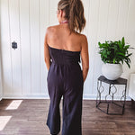 Fully lined black jumpsuit with sleeveless, ruffled bodice, smocked back, wide leg design and pockets at the pleated front.