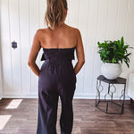 Fully lined black jumpsuit with sleeveless, ruffled bodice, smocked back, wide leg design and pockets at the pleated front.