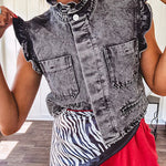 Washed black denim vest with ruffles at collar and sleeves, front pockets and silver buttons down the front.