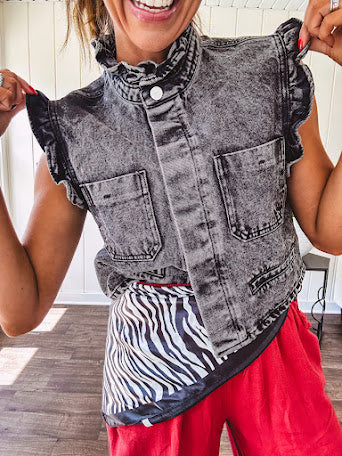 Washed black denim vest with ruffles at collar and sleeves, front pockets and silver buttons down the front.