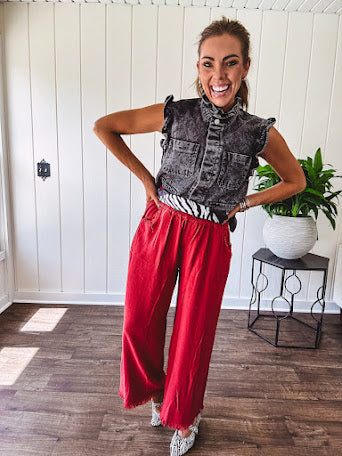 Washed black denim vest with ruffles at collar and sleeves, front pockets and silver buttons down the front.