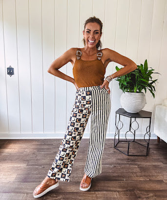 Wide leg lightweight button and zipper closure pants with elastic back waist featuring cream and black stripes down one leg and moon and star checkerboard in black, cream and mustard on the other leg.
