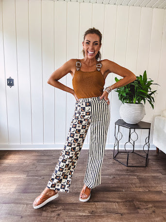 Wide leg lightweight button and zipper closure pants with elastic back waist featuring cream and black stripes down one leg and moon and star checkerboard in black, cream and mustard on the other leg.