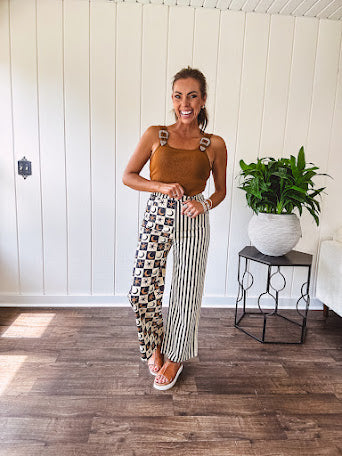 Wide leg lightweight button and zipper closure pants with elastic back waist featuring cream and black stripes down one leg and moon and star checkerboard in black, cream and mustard on the other leg.