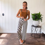 Wide leg lightweight button and zipper closure pants with elastic back waist featuring cream and black stripes down one leg and moon and star checkerboard in black, cream and mustard on the other leg.