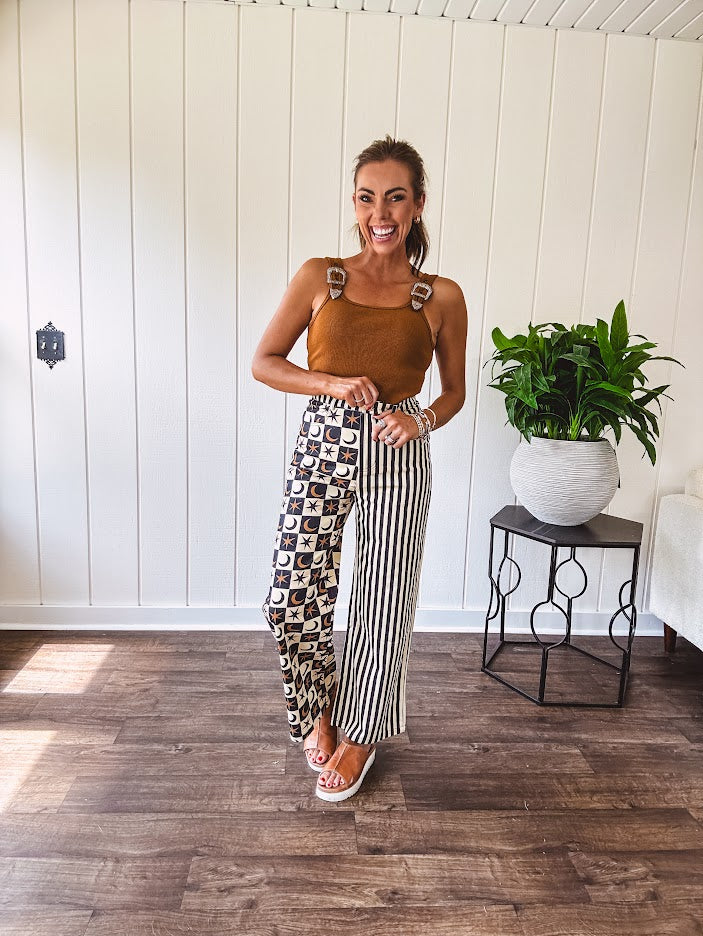 Wide leg lightweight button and zipper closure pants with elastic back waist featuring cream and black stripes down one leg and moon and star checkerboard in black, cream and mustard on the other leg.