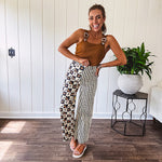 Wide leg lightweight button and zipper closure pants with elastic back waist featuring cream and black stripes down one leg and moon and star checkerboard in black, cream and mustard on the other leg.