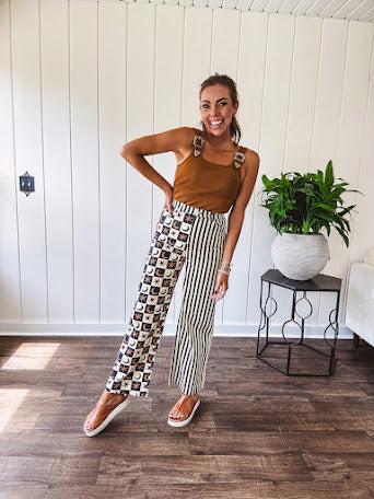 Wide leg lightweight button and zipper closure pants with elastic back waist featuring cream and black stripes down one leg and moon and star checkerboard in black, cream and mustard on the other leg.