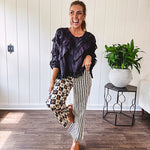 Wide leg lightweight button and zipper closure pants with elastic back waist featuring cream and black stripes down one leg and moon and star checkerboard in black, cream and mustard on the other leg.