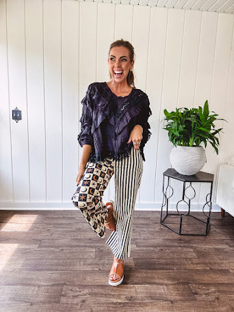 Wide leg lightweight button and zipper closure pants with elastic back waist featuring cream and black stripes down one leg and moon and star checkerboard in black, cream and mustard on the other leg.