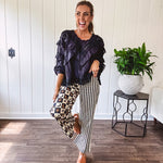 Wide leg lightweight button and zipper closure pants with elastic back waist featuring cream and black stripes down one leg and moon and star checkerboard in black, cream and mustard on the other leg.