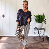 Wide leg lightweight button and zipper closure pants with elastic back waist featuring cream and black stripes down one leg and moon and star checkerboard in black, cream and mustard on the other leg.