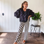 Wide leg lightweight button and zipper closure pants with elastic back waist featuring cream and black stripes down one leg and moon and star checkerboard in black, cream and mustard on the other leg.