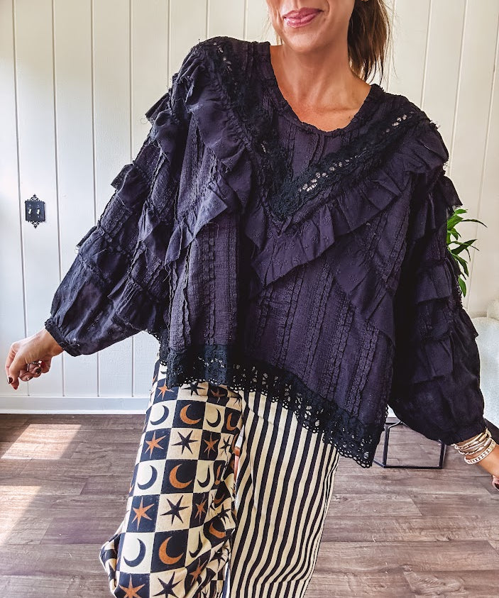 Black long sleeved blouse with lace and eyelet ruffle detail throughout.