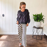Wide leg lightweight button and zipper closure pants with elastic back waist featuring cream and black stripes down one leg and moon and star checkerboard in black, cream and mustard on the other leg.