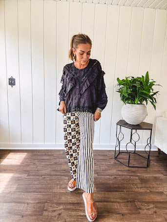 Wide leg lightweight button and zipper closure pants with elastic back waist featuring cream and black stripes down one leg and moon and star checkerboard in black, cream and mustard on the other leg.