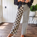 Wide leg lightweight button and zipper closure pants with elastic back waist featuring cream and black stripes down one leg and moon and star checkerboard in black, cream and mustard on the other leg.