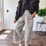 Light wash leopard print elastic waist wide leg pants with frayed hem.