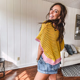 Open weave crochet sweater with 3/4 sleeves and large contrasting crochet flower on the front and contrasting trim. Oversized. Available in multiple colors.