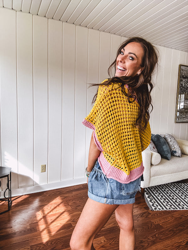Open weave crochet sweater with 3/4 sleeves and large contrasting crochet flower on the front and contrasting trim. Oversized. Available in multiple colors.