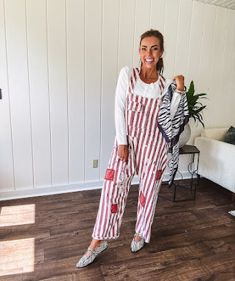 Cream and crimson striped overalls with button adjustable straps and sides with paint splatter and patchwork detail throughout.