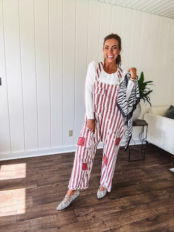 Cream and crimson striped overalls with button adjustable straps and sides with paint splatter and patchwork detail throughout.
