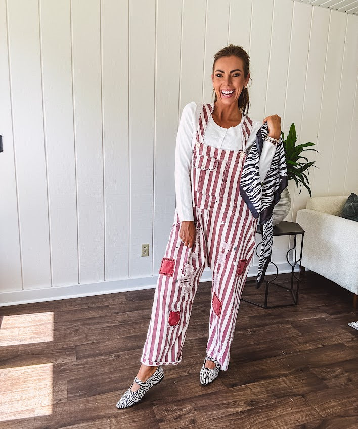 Cream and crimson striped overalls with button adjustable straps and sides with paint splatter and patchwork detail throughout.