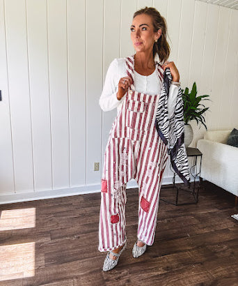 Cream and crimson striped overalls with button adjustable straps and sides with paint splatter and patchwork detail throughout.