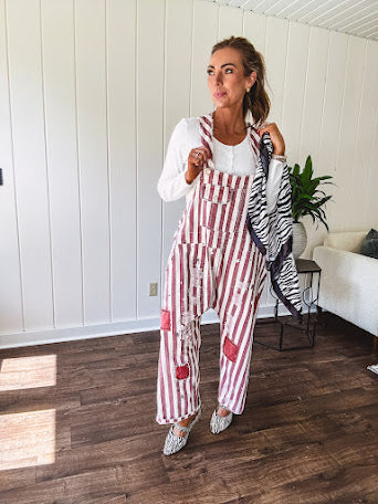 Cream and crimson striped overalls with button adjustable straps and sides with paint splatter and patchwork detail throughout.