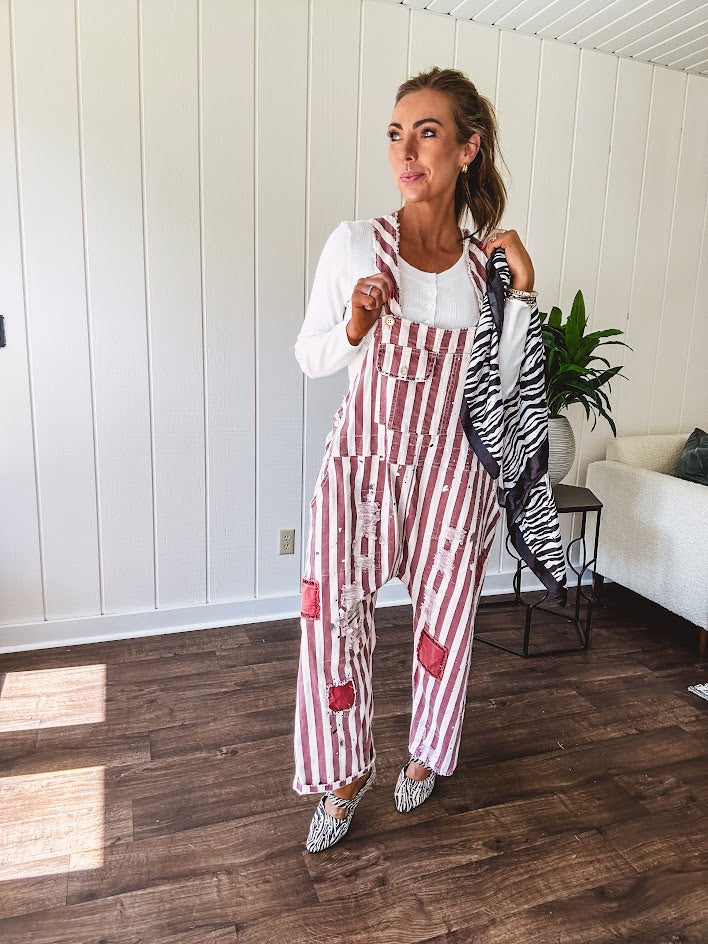 Cream and crimson striped overalls with button adjustable straps and sides with paint splatter and patchwork detail throughout.