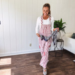 Cream and crimson striped overalls with button adjustable straps and sides with paint splatter and patchwork detail throughout.