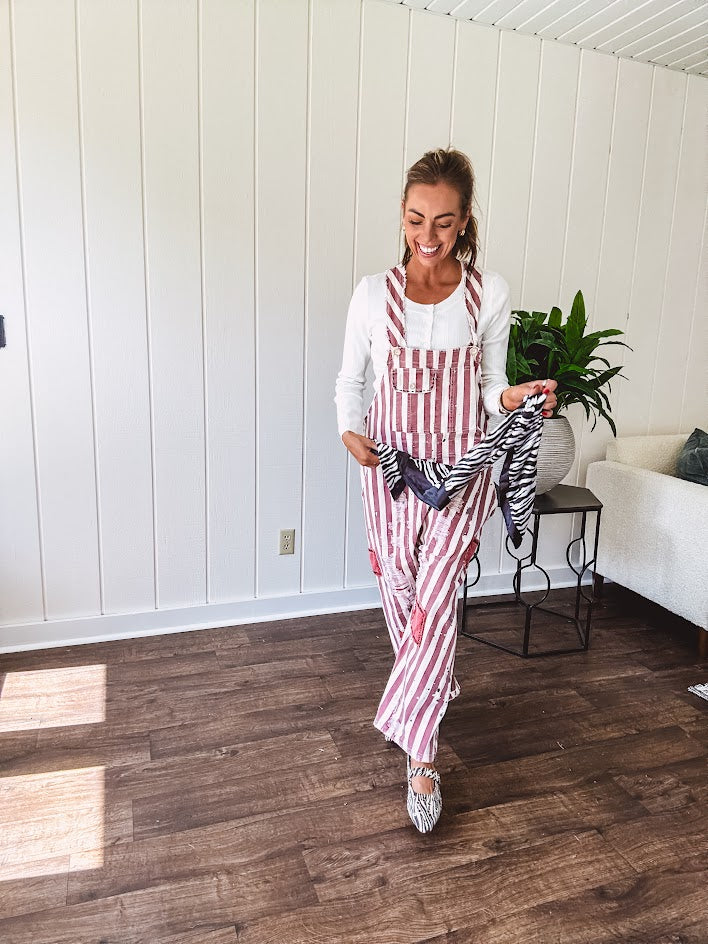 Cream and crimson striped overalls with button adjustable straps and sides with paint splatter and patchwork detail throughout.
