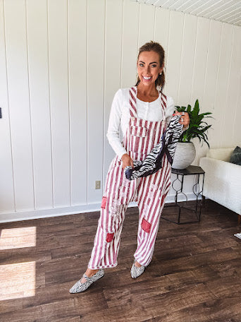 Cream and crimson striped overalls with button adjustable straps and sides with paint splatter and patchwork detail throughout.