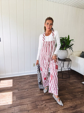 Cream and crimson striped overalls with button adjustable straps and sides with paint splatter and patchwork detail throughout.